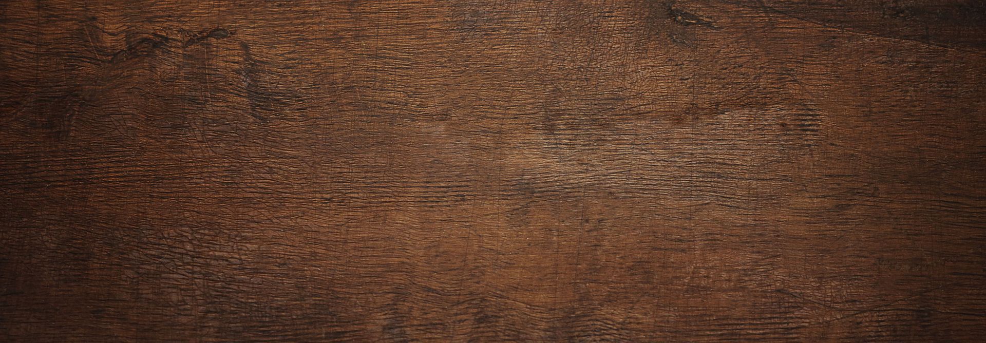 Détail d'une surface en bois foncé montrant le veinage naturel du matériau.