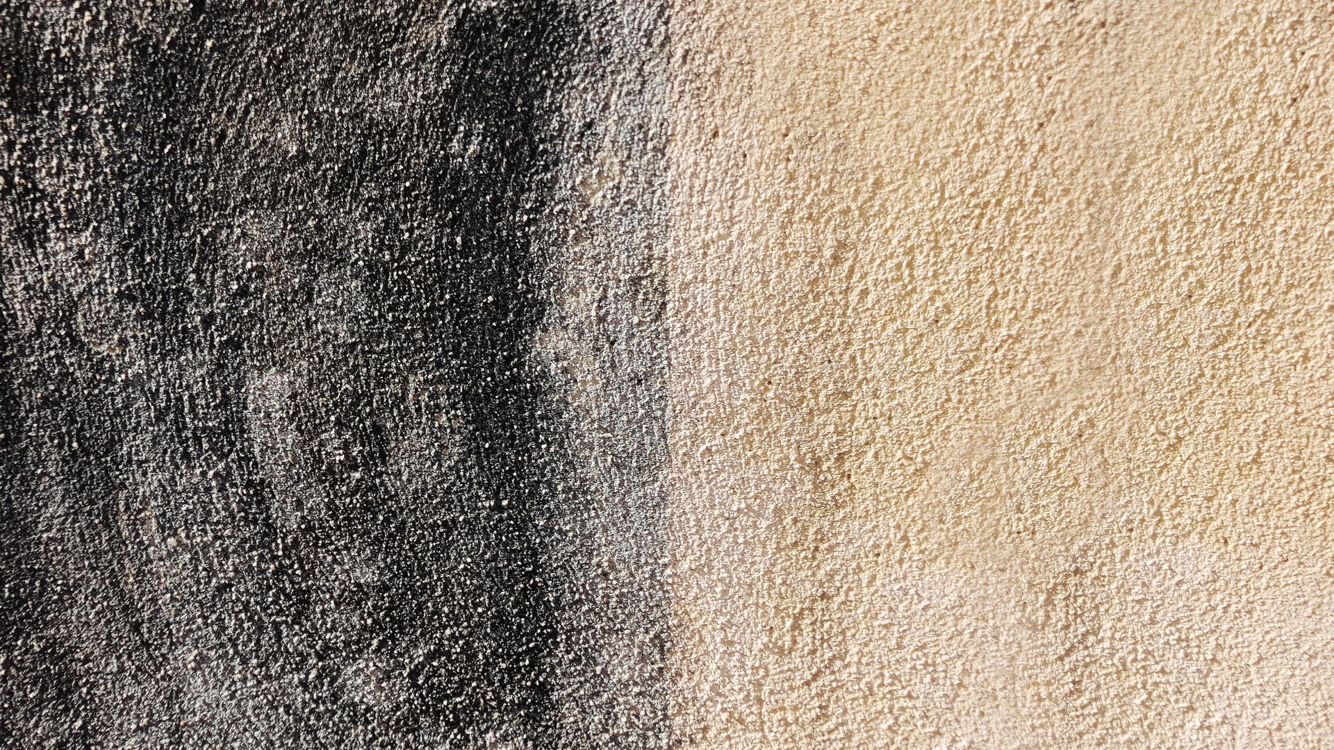 Surface de mur crépi présentant une zone sombre verticale à gauche et une zone claire à droite