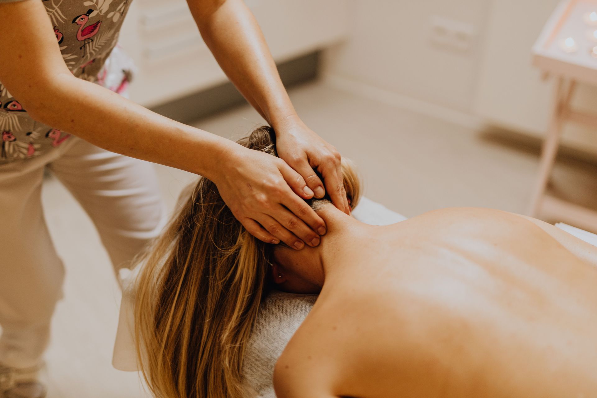 Una masajista masajea el cuello y los hombros de un cliente en una luminosa sala de spa.