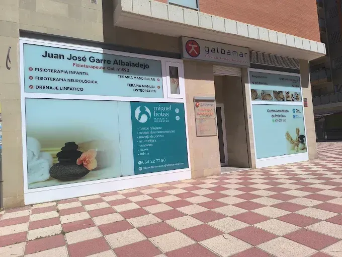 Fachada de la clínica con letreros en español, ventanas de cristal y un pasillo de baldosas rojas y crema.