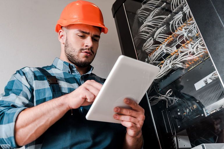 Ein Mann mit Schutzhelm benutzt einen Tablet-Computer.