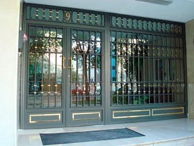 Puerta metálica de color gris con paneles de vidrio y rejas de seguridad; puerta marcada con el número 9.