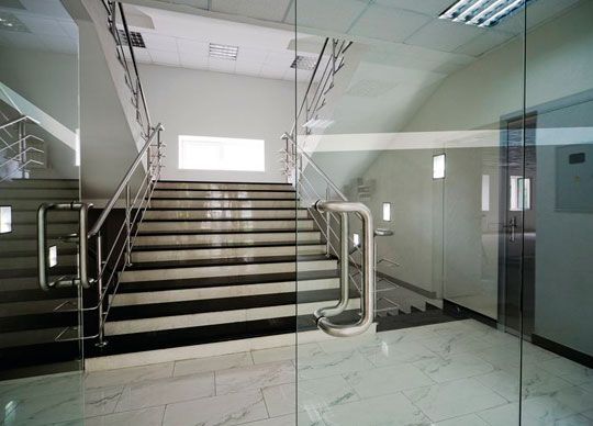 Escalera con paredes de cristal y barandillas metálicas en el interior de un edificio.