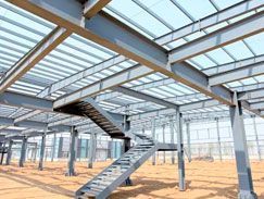 Marco estructural de acero de un edificio en construcción, incluyendo vigas, columnas y una escalera.