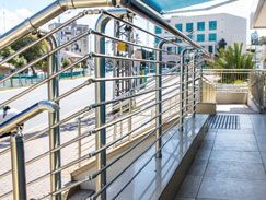 Pasamanos de acero inoxidable a lo largo de una rampa y escaleras que conducen a la entrada de un edificio.