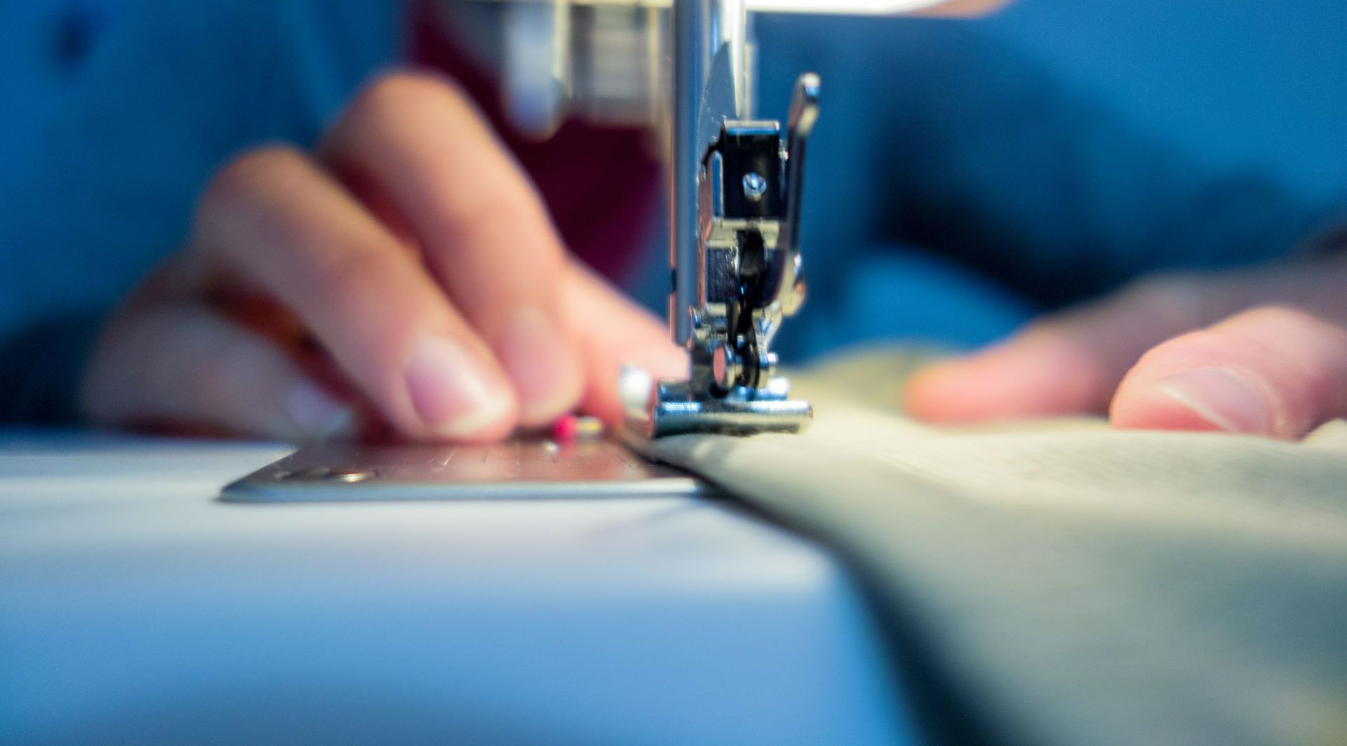 Une personne en train de coudre un textile à la machine.