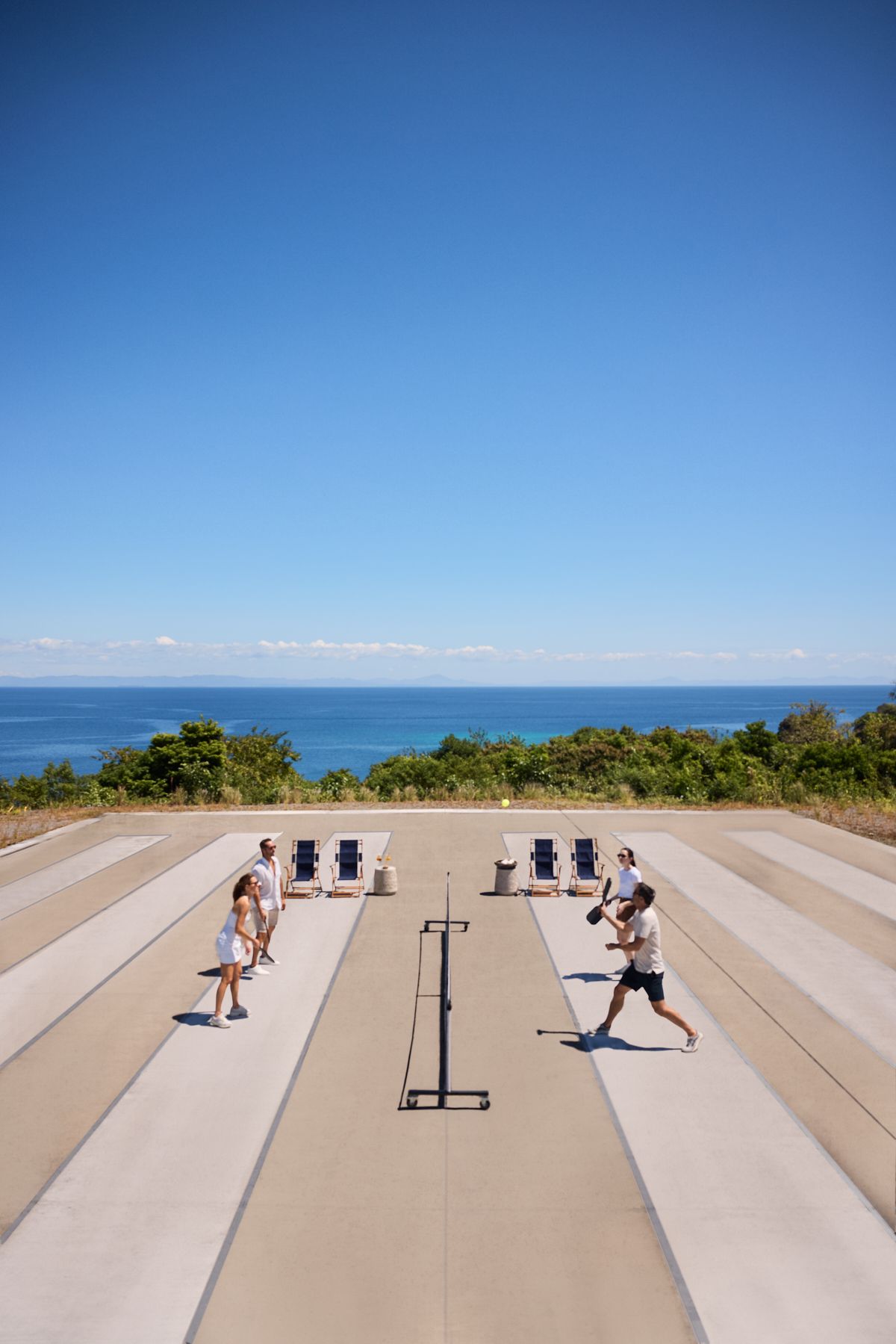 Des personnes font de l'exercice sur une terrasse en bord de mer avec l'océan en arrière-plan.
