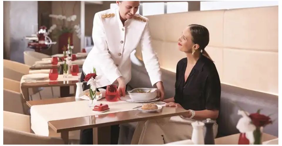 Un serveur apporte des boissons et un dessert à une femme assise à une table de restaurant.