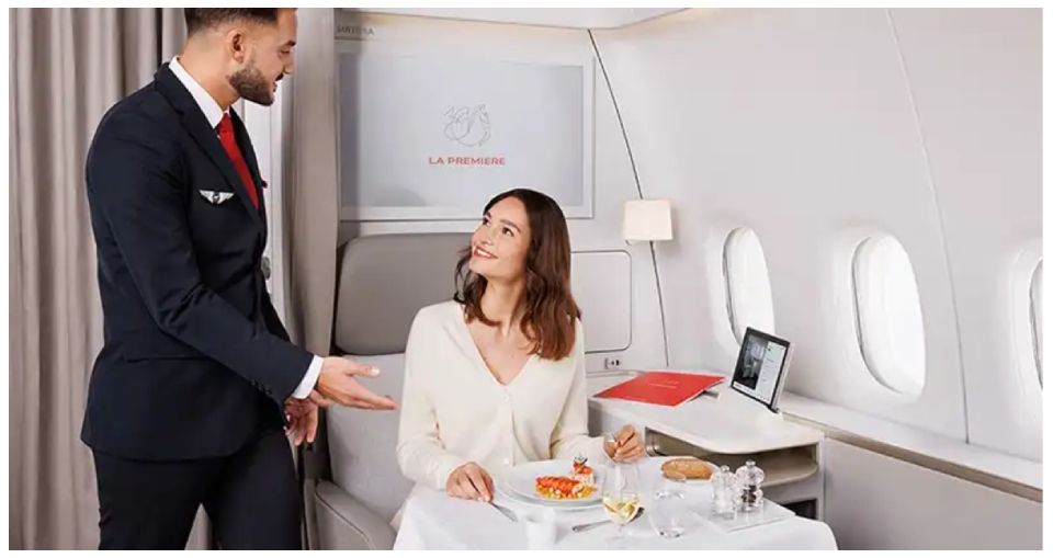 Hôtesse de l'air servant un passager assis à une table dans la cabine d'un avion