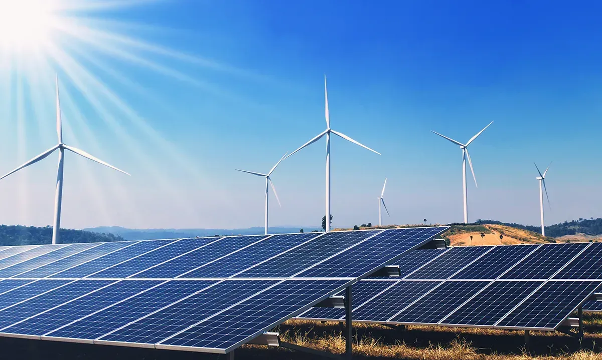 Ein Feld aus Solarmodulen und Windturbinen an einem sonnigen Tag.