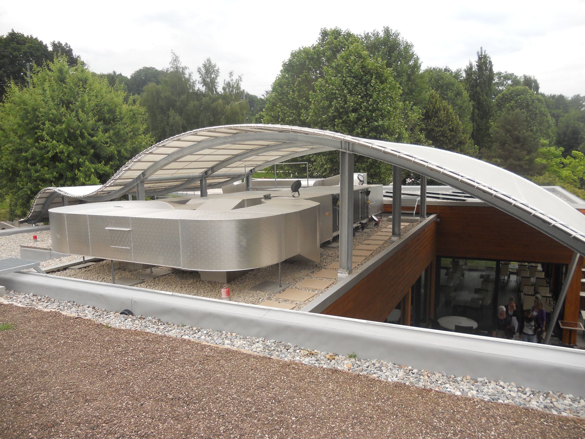 Une structure de toit incurvée et translucide recouvre un système de climatisation métallique