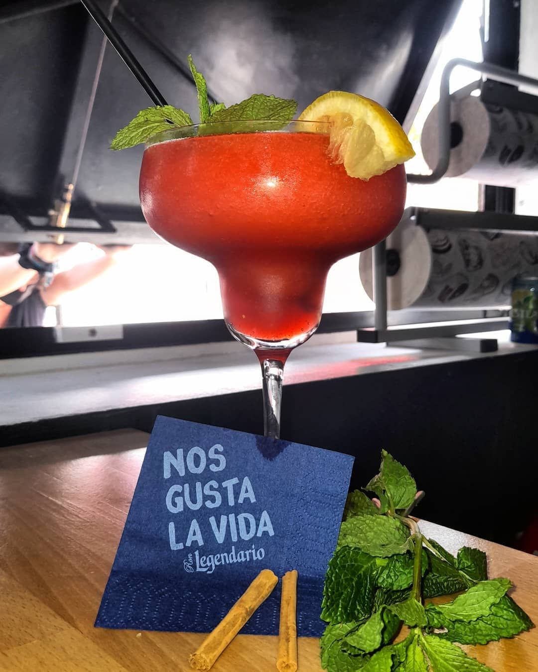 Cóctel rojo en una copa con tallo y guarnición de limón