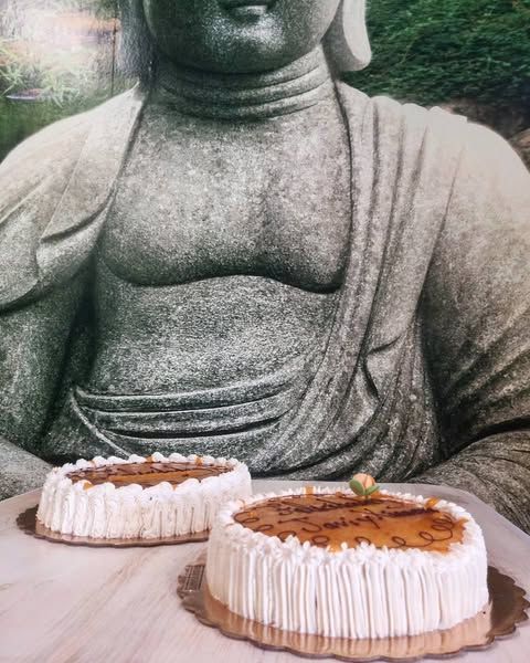 Dos pasteles redondos frente a una estatua de Buda de piedra al aire libre.