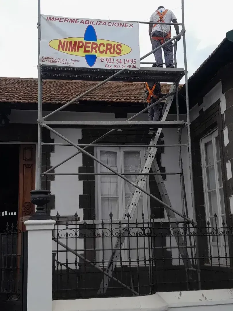 Un hombre está de pie en un andamio frente a un edificio.