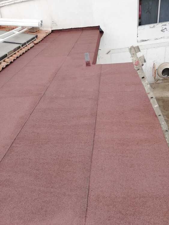 Un techo rojo con un edificio blanco al fondo