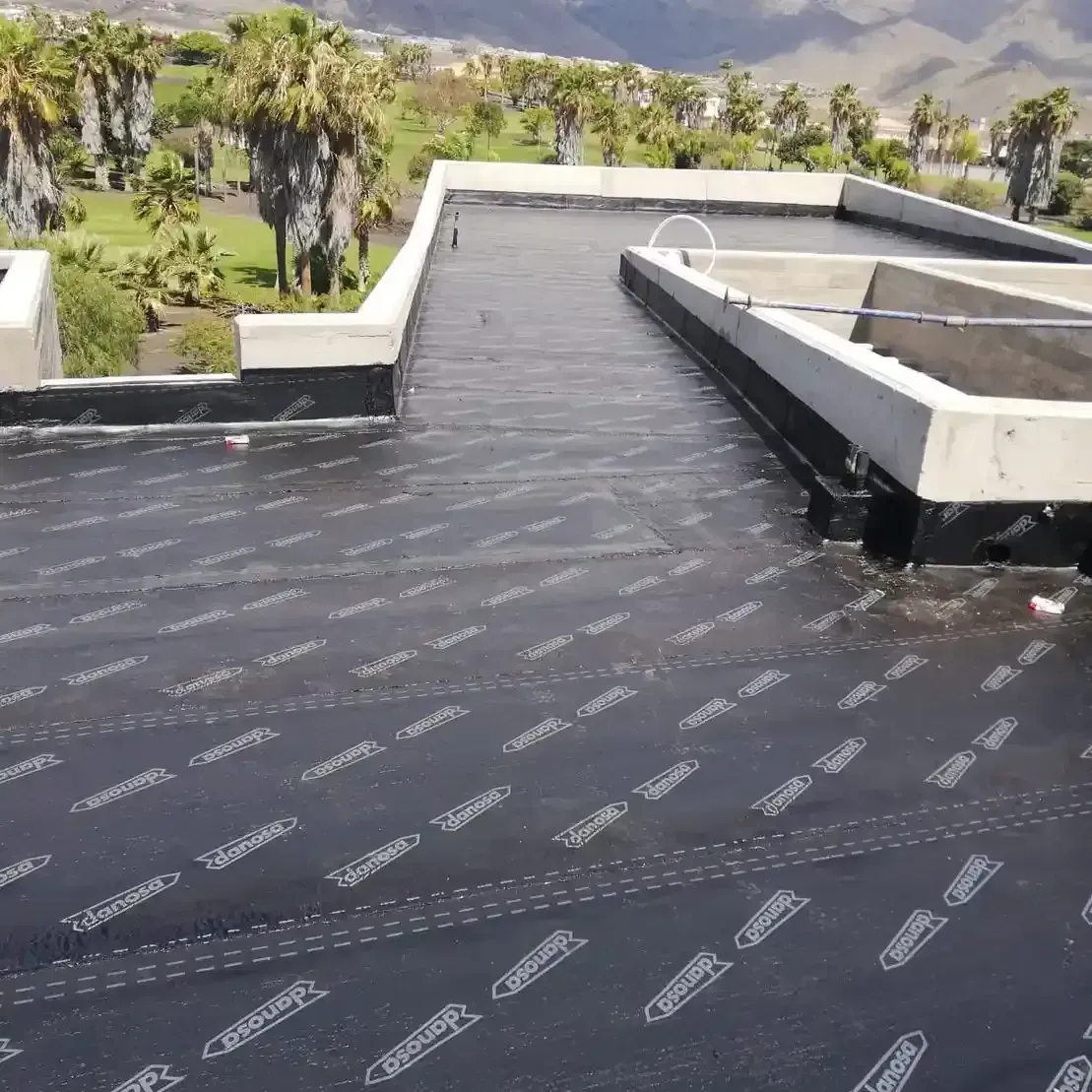 Un techo negro con algunos árboles al fondo.