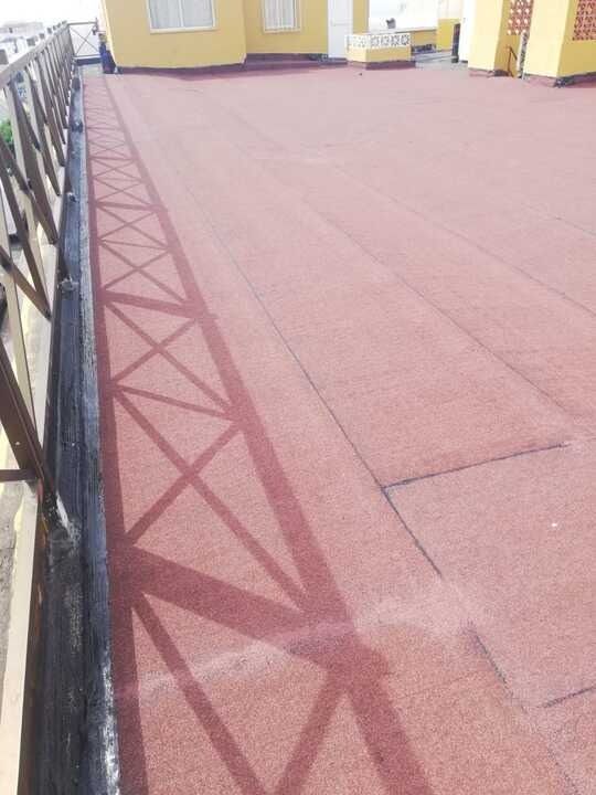 Un techo rojo con una barandilla negra en el costado de un edificio.