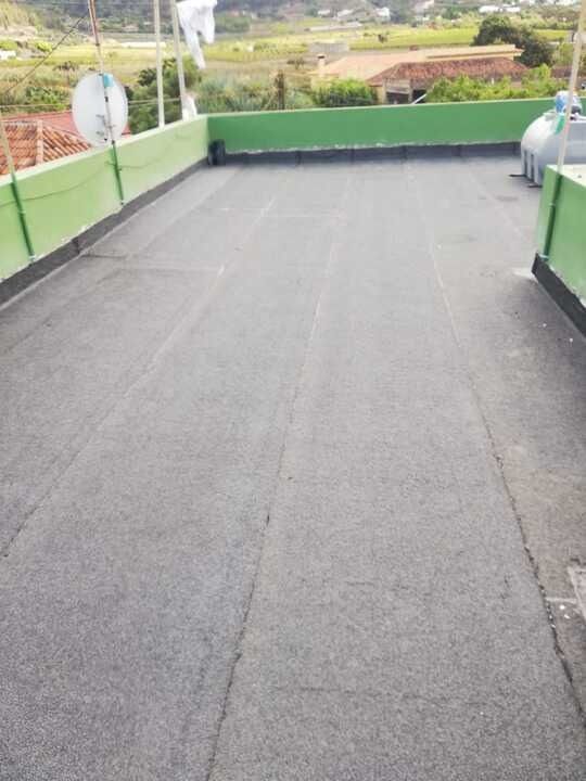 Un techo con una valla verde y una antena parabólica.