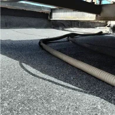 Una manguera está tendida en el suelo debajo de un puente.