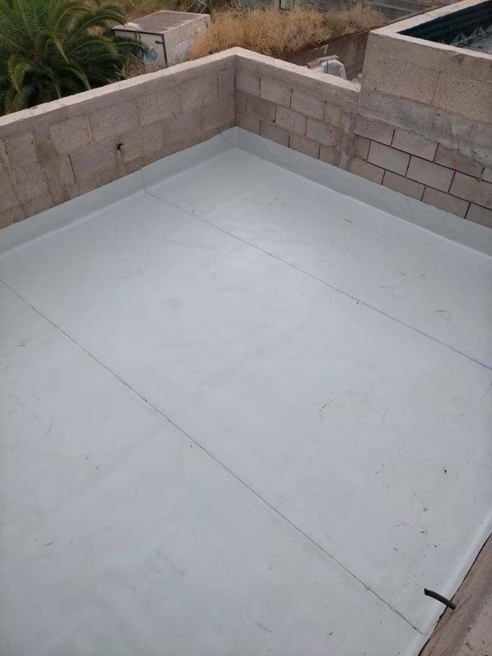 Un techo blanco con una pared de ladrillo y una piscina al fondo.