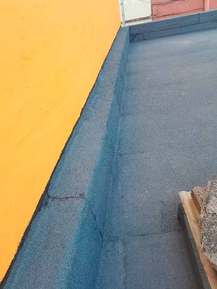 Un primer plano de un techo con una pared amarilla al fondo.