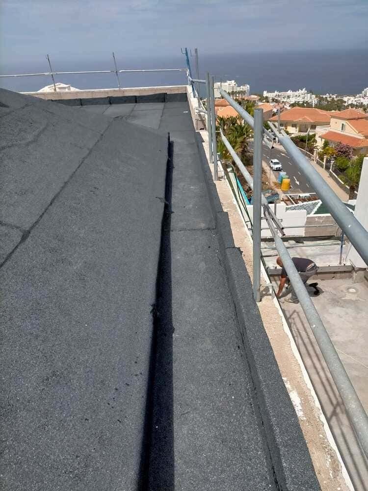 Un techo con barandilla de metal y vista al mar.