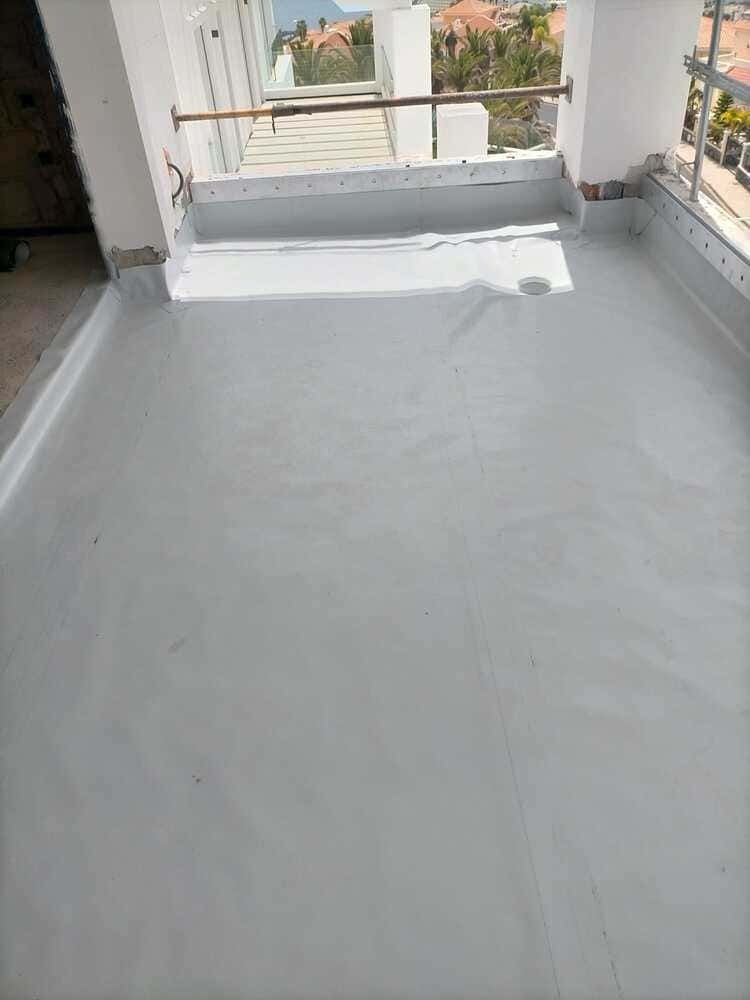 Un balcón con techo gris y una ventana.