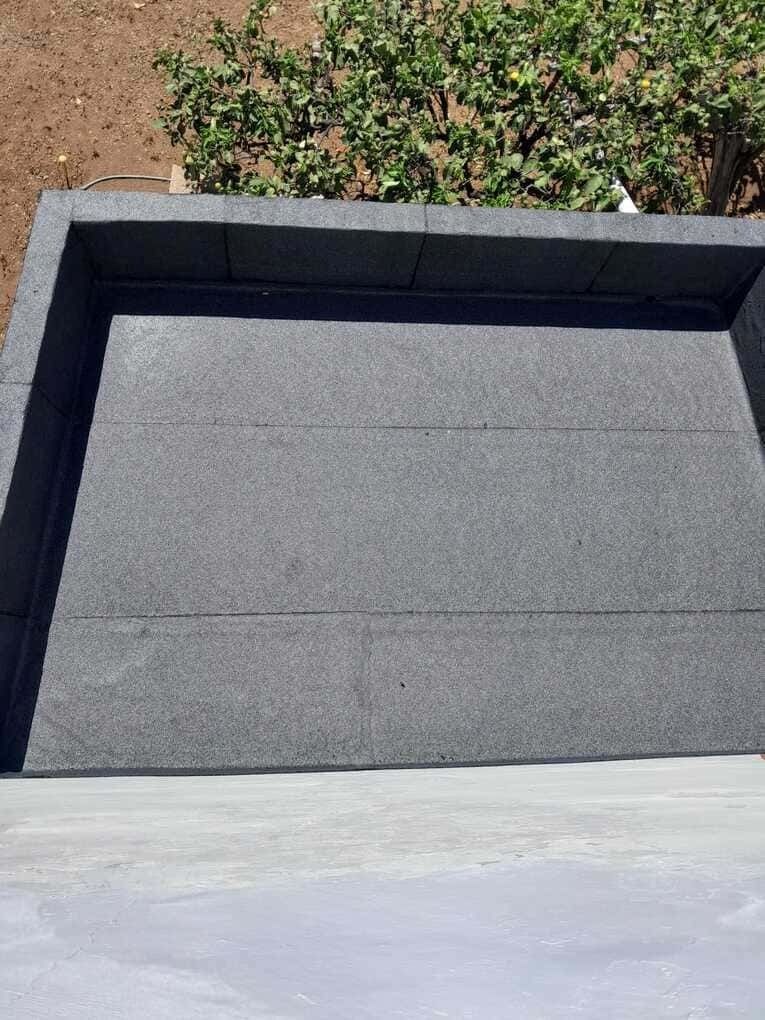 Una bandeja negra reposa sobre una superficie de hormigón.