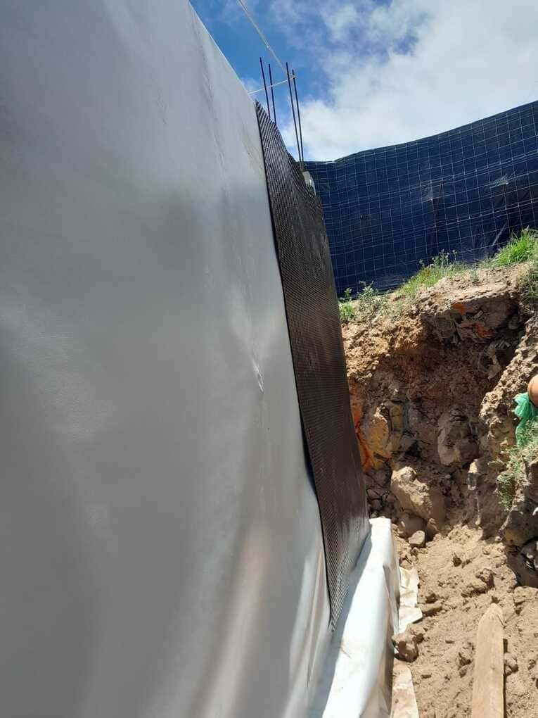 Una persona está cavando un hoyo en la tierra al lado de una pared.