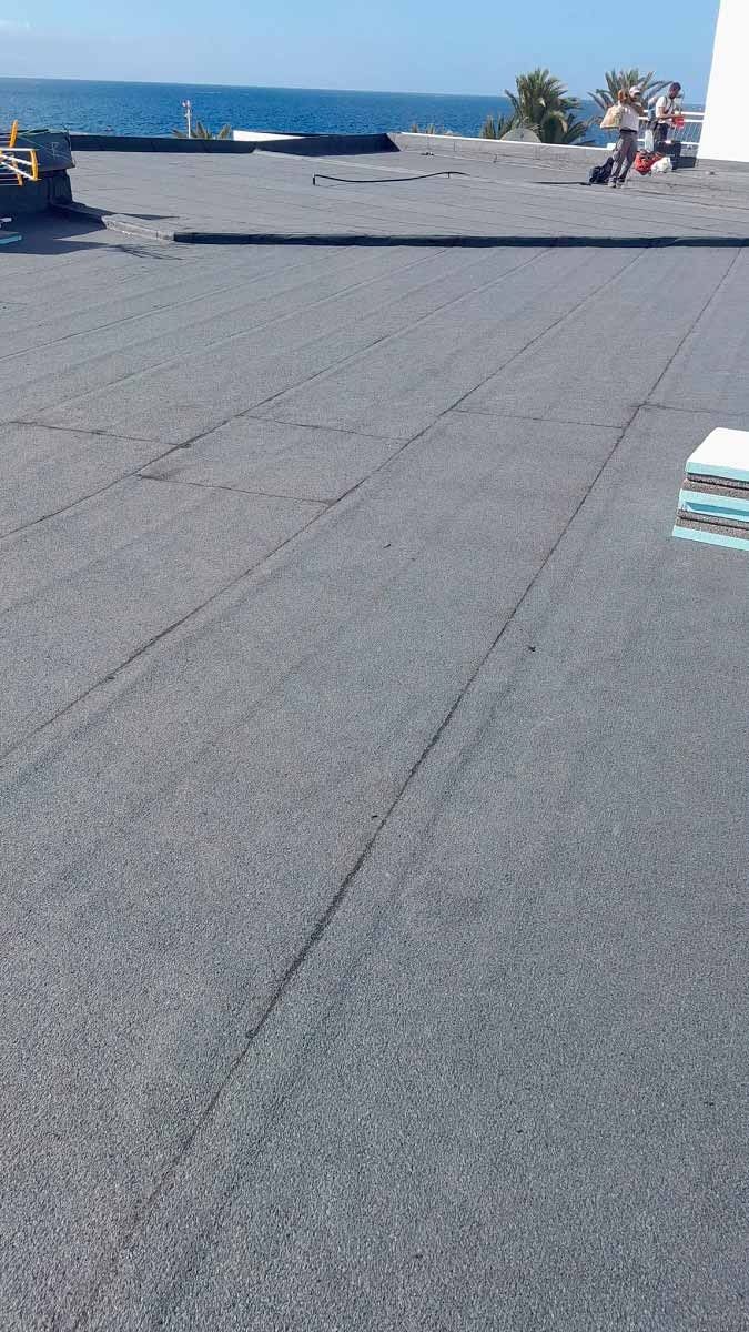 Un grupo de personas está de pie en un tejado con vistas al océano.