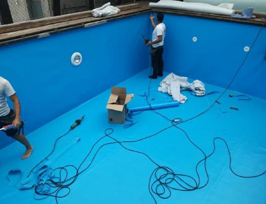 Dos hombres están trabajando en una piscina azul.