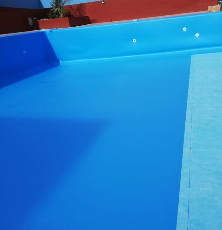 Una gran piscina azul con una pared roja al fondo.