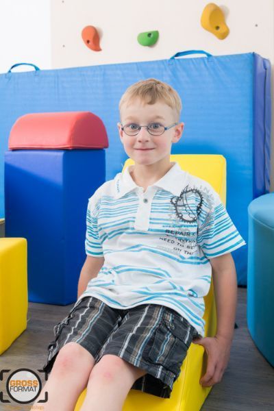 Kind sitzt auf einem gelben Sitz