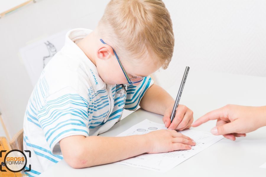 Kind wird bei Zeichnen Übungen unterstützt