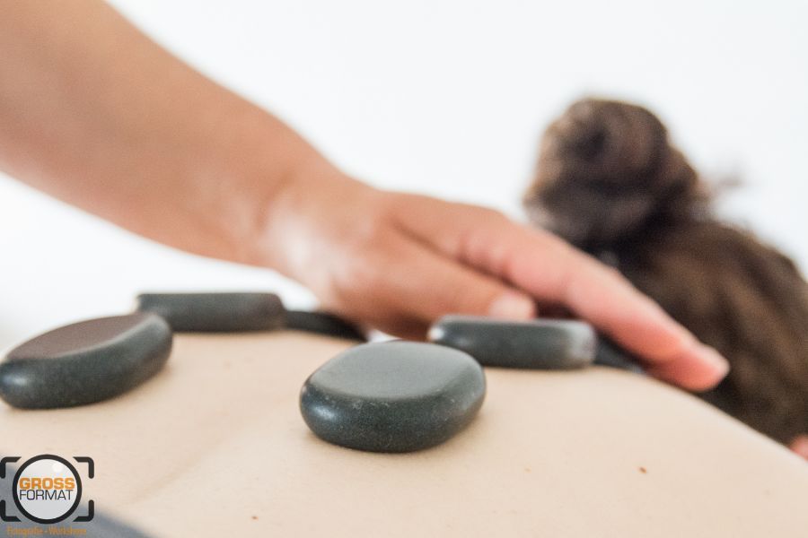 Hot Stone Massage mit Hand der Therapeutin