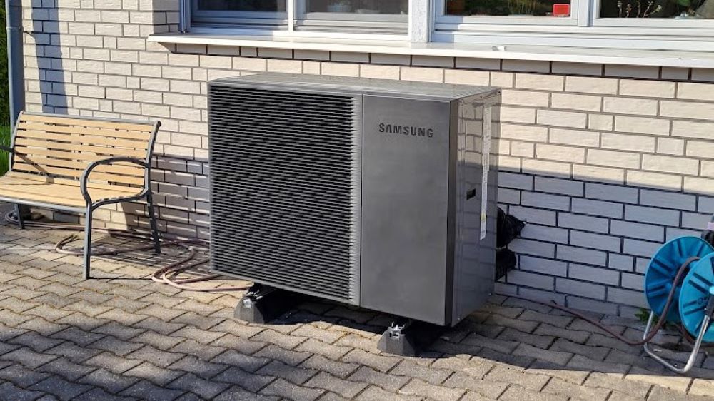 An der Seite eines Backsteingebäudes steht eine große Wärmepumpe.