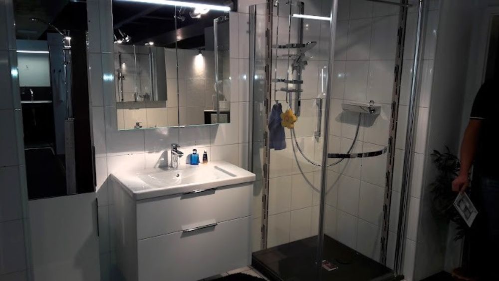 Ein Badezimmer mit Waschbecken, Spiegel und Duschkabine.