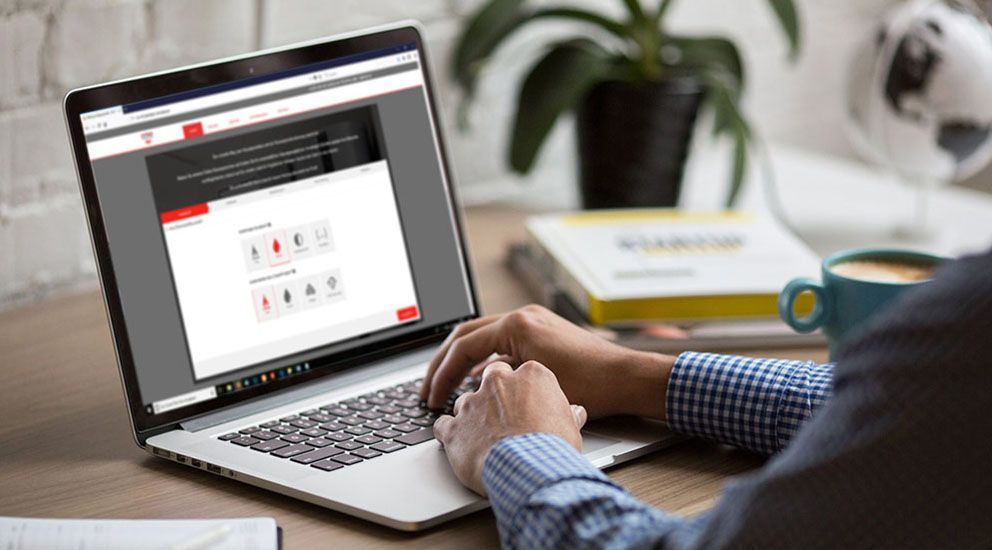 Ein Mann tippt an einem Schreibtisch auf einem Laptop.