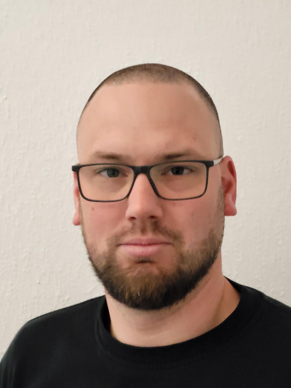 Ein Mann mit Bart und Brille trägt ein schwarzes Hemd.