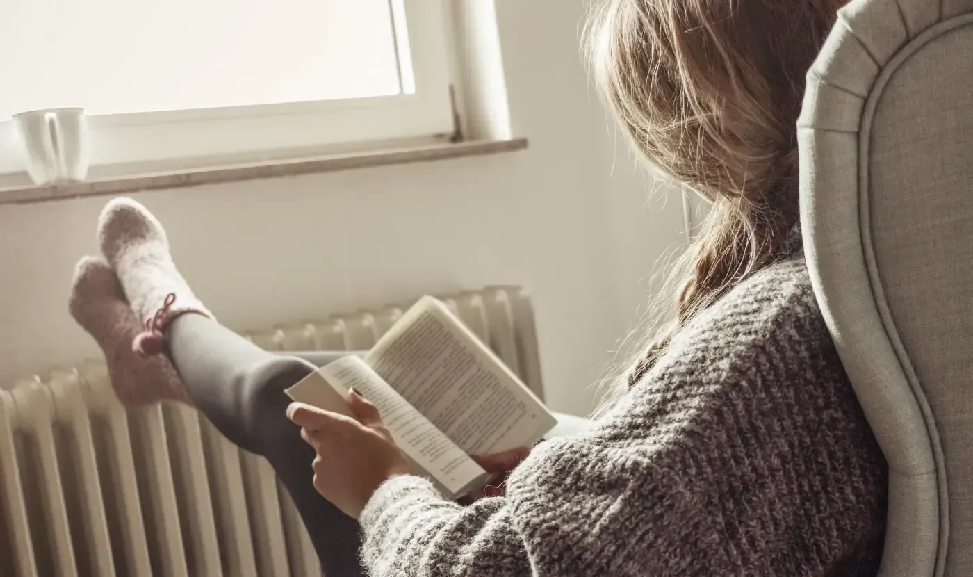 Eine Frau sitzt auf einem Stuhl und liest ein Buch.