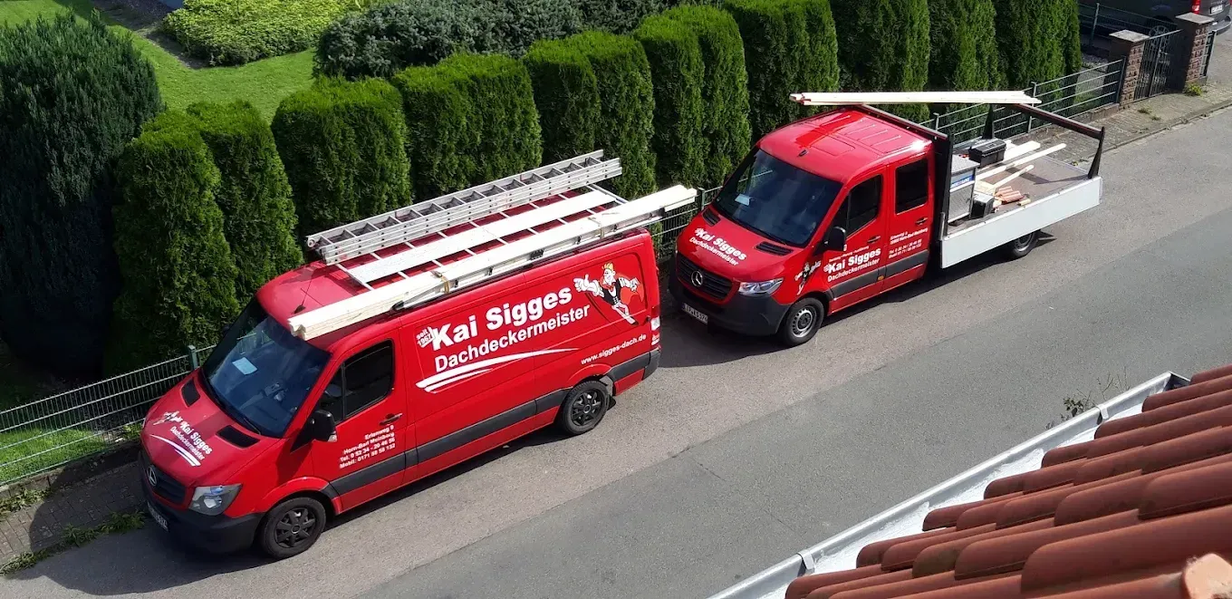 Zwei rote Lieferwagen stehen nebeneinander am Straßenrand