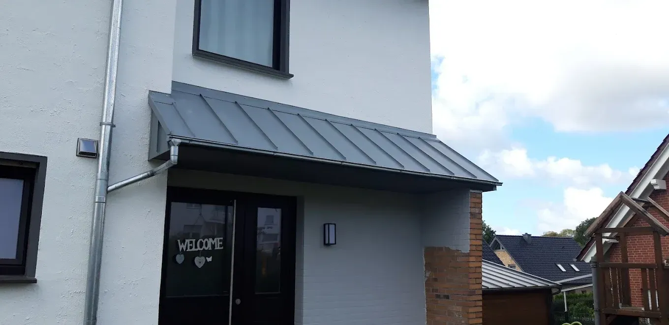 Ein weißes Haus mit einem grauen Dach und einer schwarzen Tür