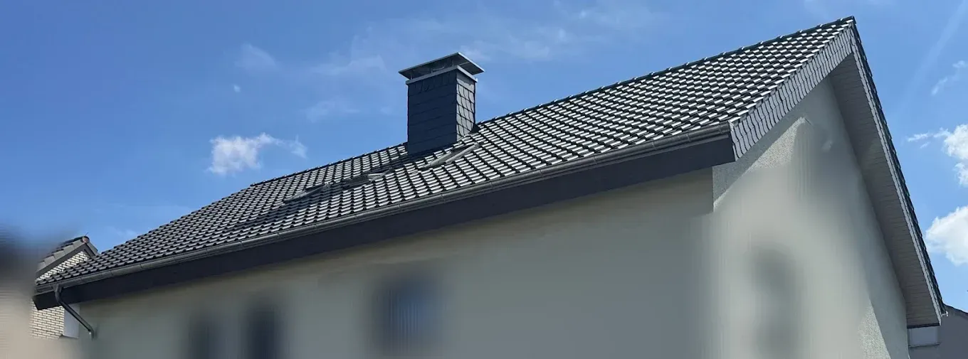 Ein Haus mit einem Schornstein auf dem Dach und einem blauen Himmel im Hintergrund