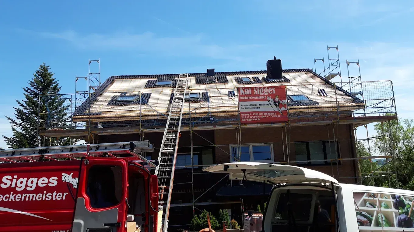 Ein roter Lieferwagen parkt vor einem im Bau befindlichen Haus
