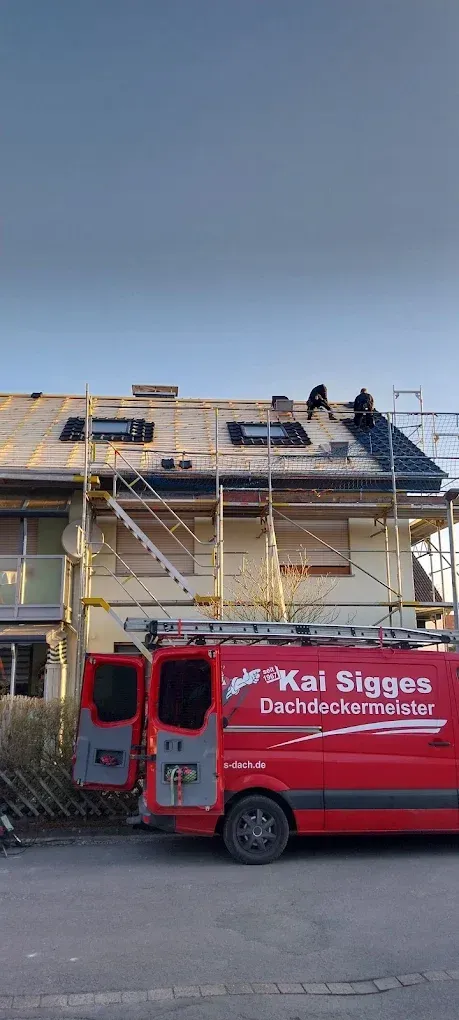 Ein roter Lieferwagen parkt vor einem im Bau befindlichen Haus