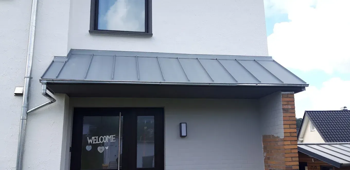 Ein weißes Haus mit einer schwarzen Tür und einem Metalldach