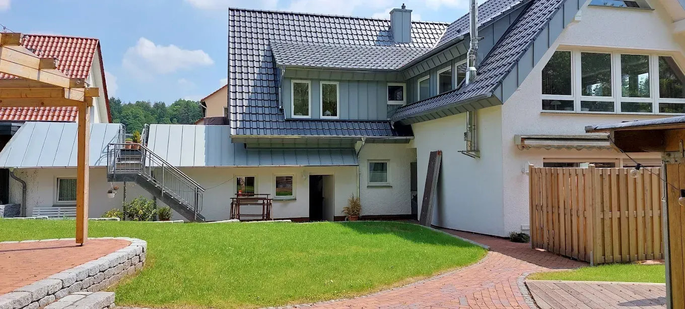 Ein großes weißes Haus mit rotem Dach ist von Gras und einem Holzzaun umgeben