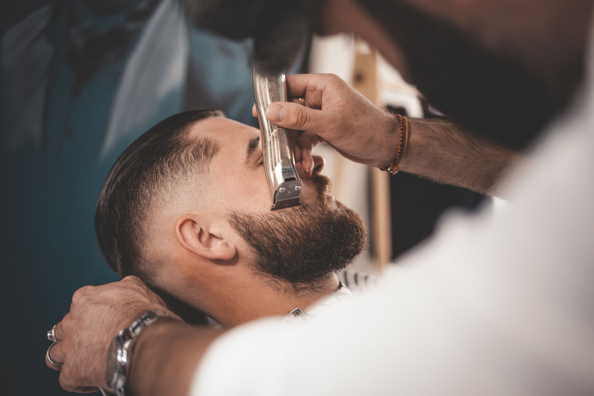 Un homme se fait raser la barbe par un coiffeur dans un salon de coiffure.