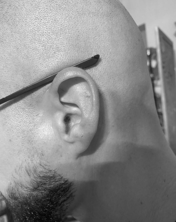 Un gros plan de l'oreille d'un homme portant des lunettes.