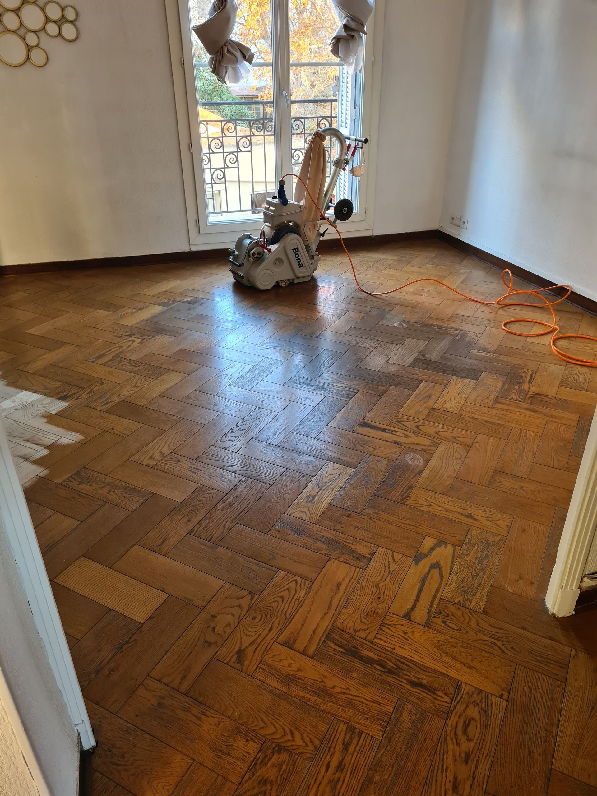 Machine de ponçage dans une pièce au parquet à chevrons
